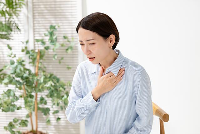 胸に手を当て咳き込んでいる女性